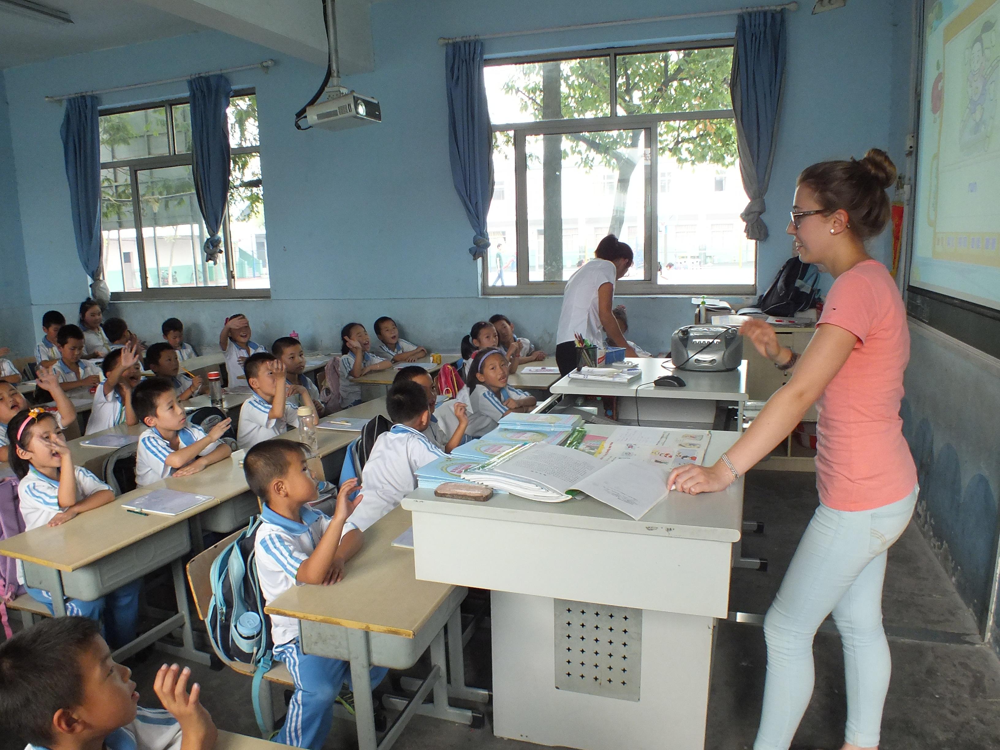 An English language teacher addresses her class during her teaching work experience in China Young students put up their hands to answer the Projects Abroad volunteer teaching English in China